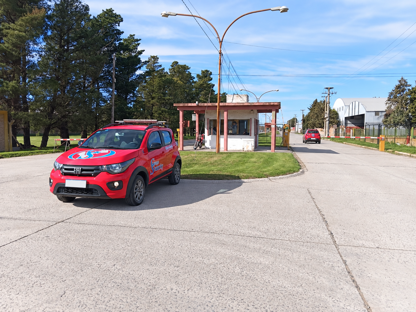 Dos vehículos rojos de Grupo Security en la entrada de un parque industrial
